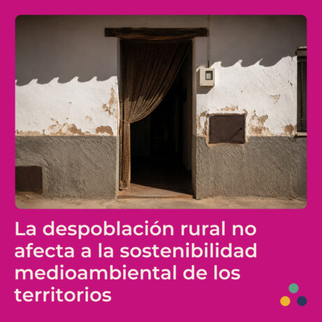 Fachada de una vivienda rural antigua con paredes encaladas y deterioradas, una puerta abierta con una cortina de tiras y una ventana en un lateral. La imagen está enmarcada sobre un fondo fucsia y acompañada del texto: “La despoblación rural no afecta a la sostenibilidad medioambiental de los territorios”. En la esquina inferior derecha aparecen tres círculos de colores como elementos decorativos.